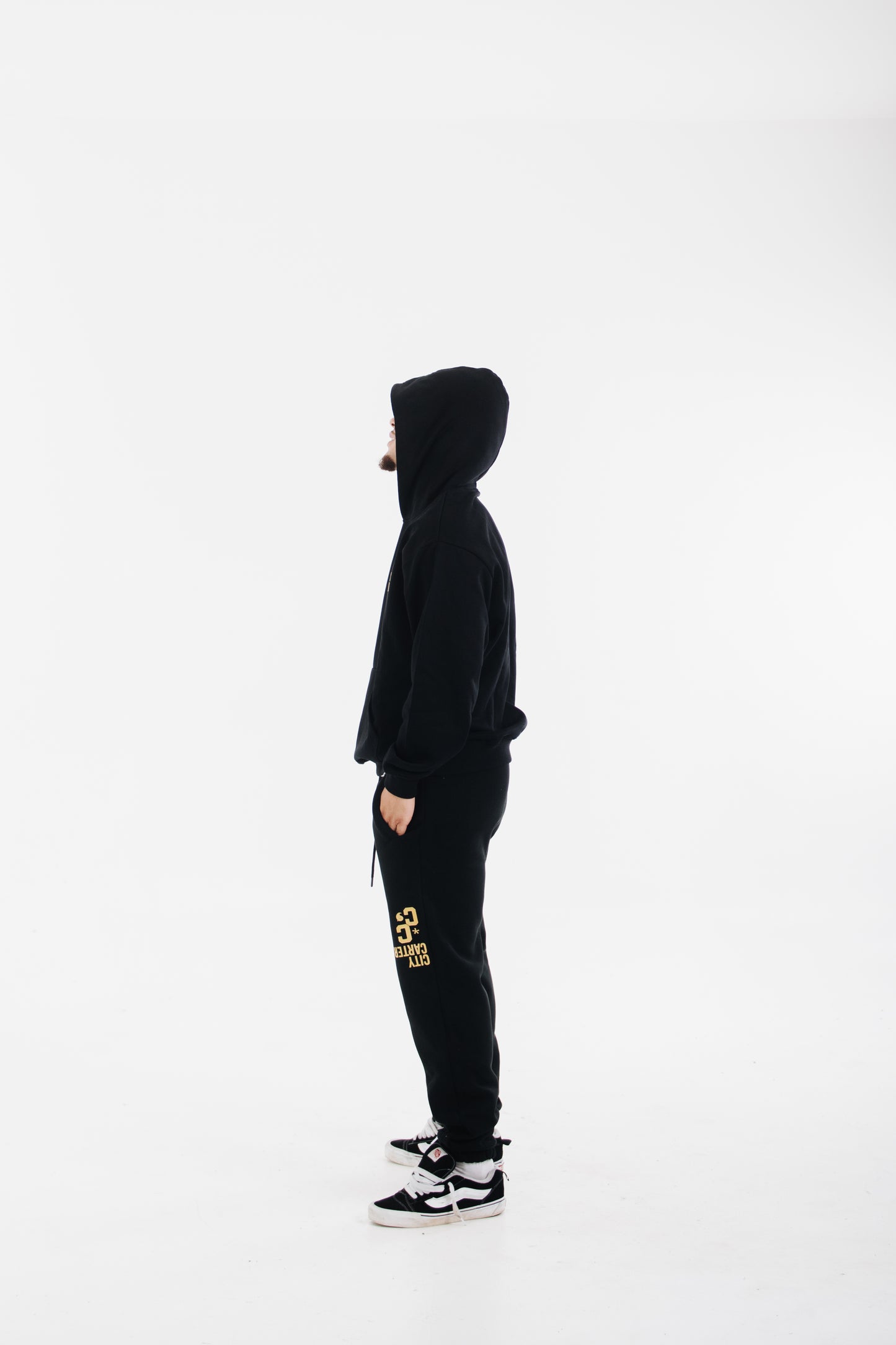 Model wearing black tracksuit with yellow chest logo and printed pants
