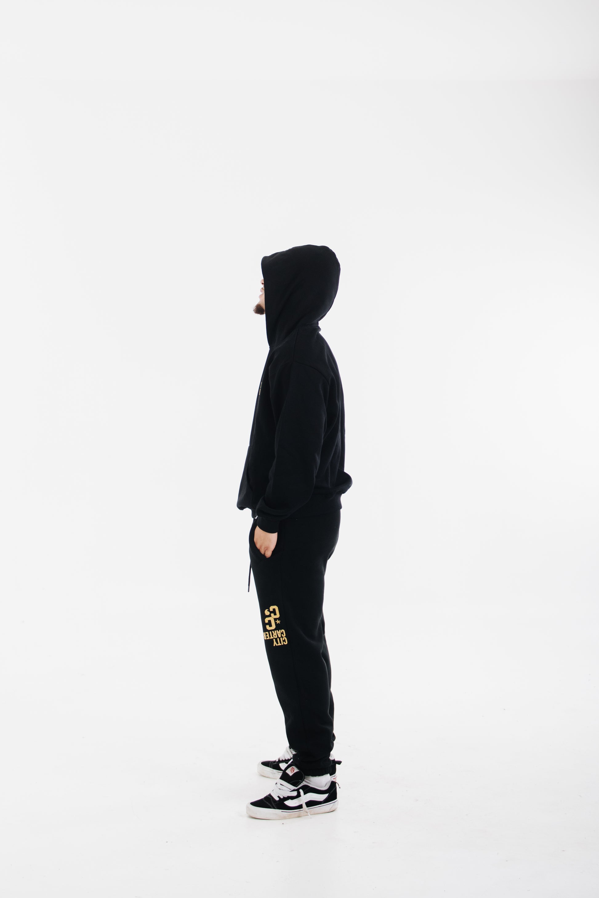 Model wearing black tracksuit with yellow chest logo and printed pants